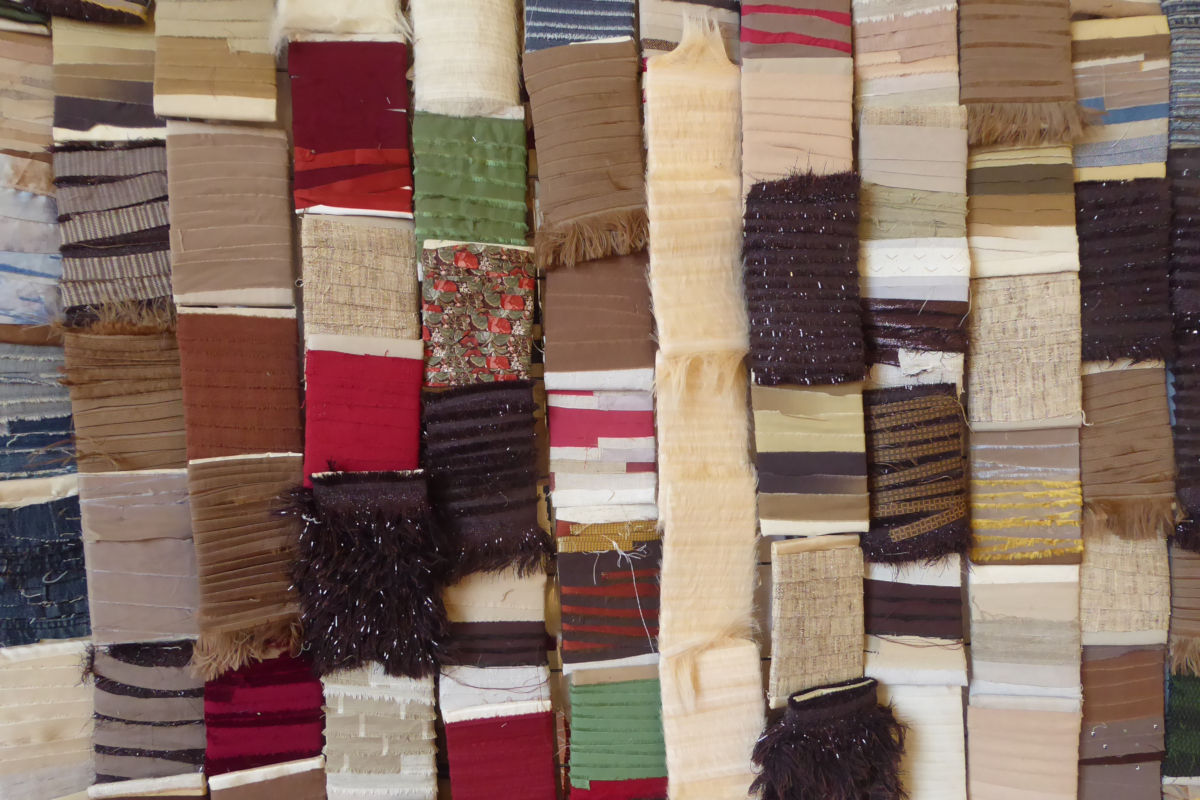 FITE 2020 Regards textiles sur les tapisseries de la Chaise-Dieu, détail ©Thomas Leveugle Stack of fabric swatches in neutral and earth tones with varied textures and fringed edges.