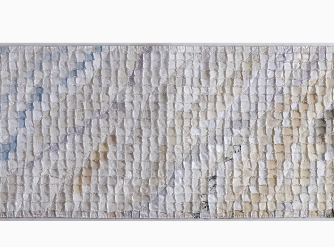 Abstract textile wall hanging made of tiny pastel fabric squares in a grid, featuring pale blues, pinks, and creams.