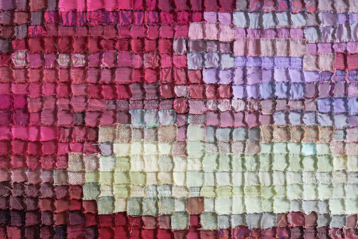 Sabine Cibert Boréale 295 détail ©Pascal Muradian Close-up of a quilted patchwork with small fabric squares in a magenta-to-pale-yellow gradient.