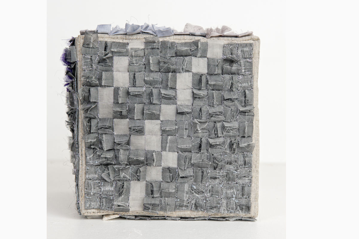Sabine Cibert- L ira del cielo ©Pascal Muradian Grey patchwork textile cube/art object made from woven fabric squares on a light background