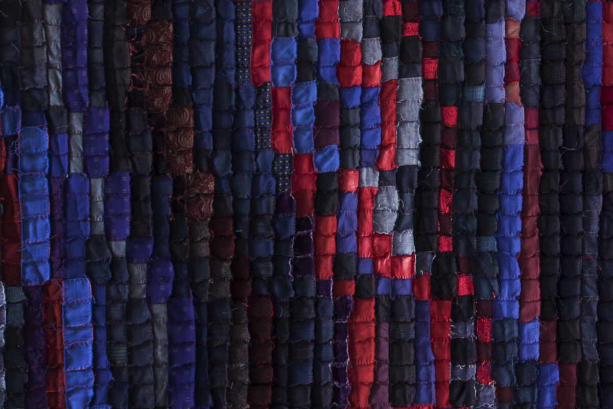 Sabine Cibert Magma 1 détail ©Philippe-Liev Pourcelot Close-up of a patchwork quilt with vertical fabric strips in blues, reds, and purples.