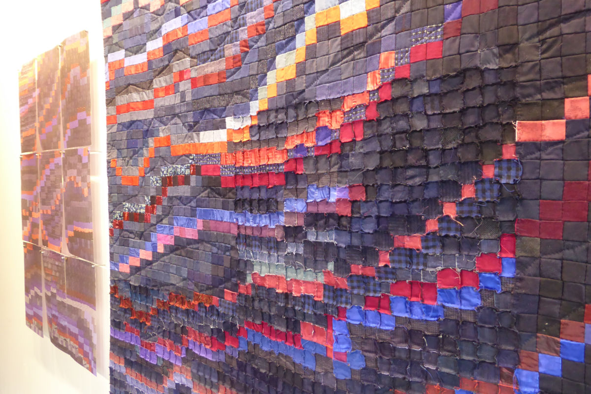 Sabine Cibert - Magma et son archétype détail ©Thomas Leveugle Large quilted wall art made of small fabric squares in purple, blue, and red hues.