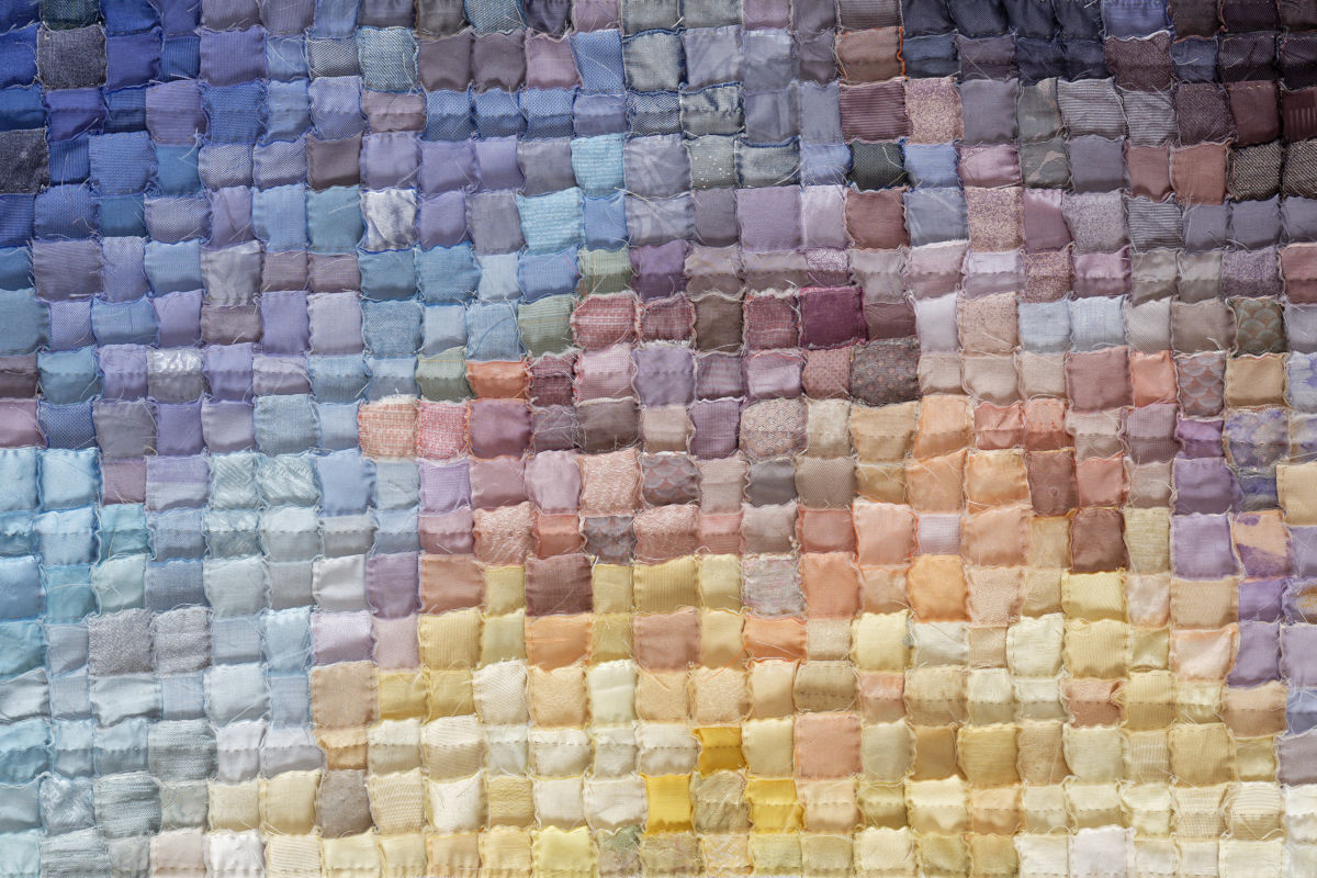 Patchwork quilt in a gradient from deep blues and purples at top to soft yellows at bottom.