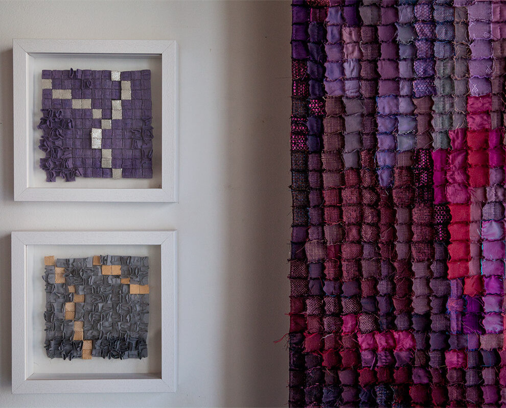 Sabine Cibert Orage 322 Orage301 Boreale295, détail ©Philippe-Liev Pourcelot Two white-framed textile art pieces mounted on a light wall, each featuring purple and gray square patches; a large multicolor patchwork textile hangs to the right.