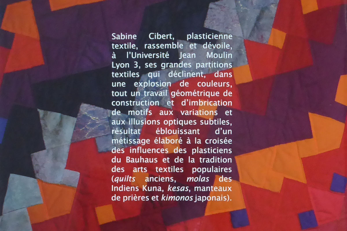 Sabine Cibert Partitions textiles publication Universite Jean-Moulin Lyon3 Verso présentation Block of French text describing Sabine textile artist and her color partitions inspired by Bauhaus on a patchwork quilt.
