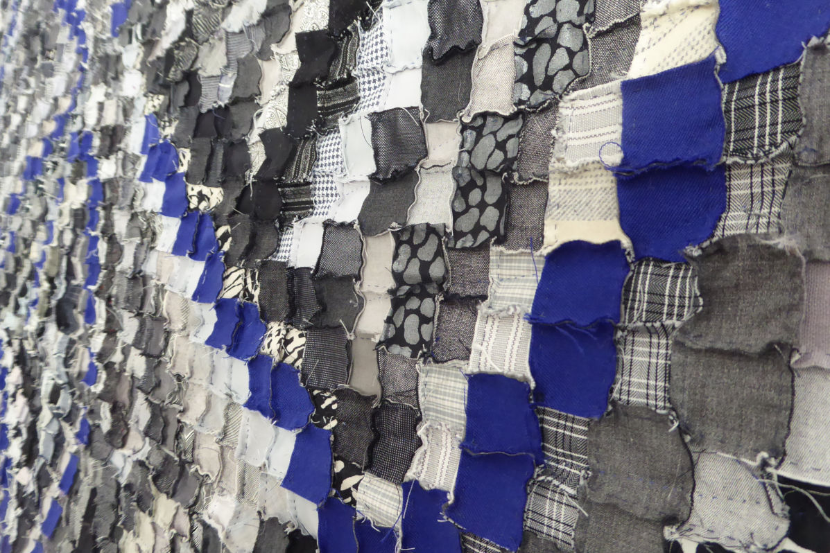 Sabine Cibert Sémagramme 216 détail ©Pascal Muradian Wall installation made of overlapping blue, gray, and black fabric scraps in a mosaic pattern