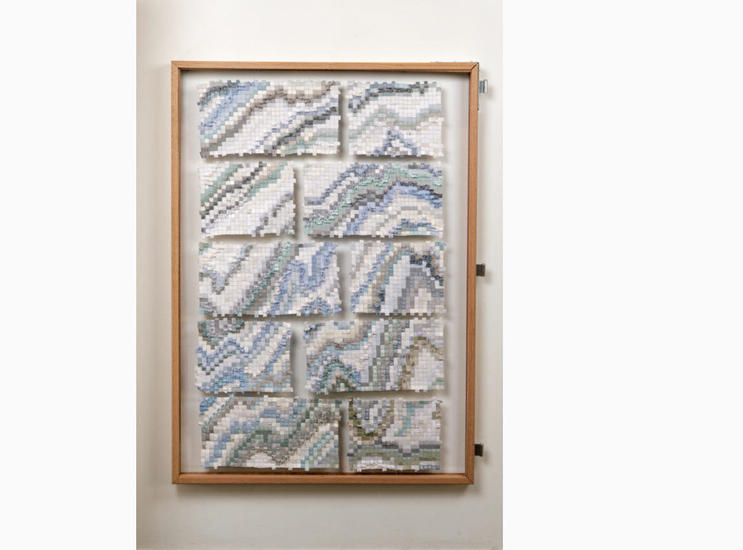 Sabine-Cibert Sikuliaq face A ©Pascal Muradian Framed wooden display with nine mosaic tile panels forming blue-gray wave patterns in white, arranged in a grid inside a light wood frame