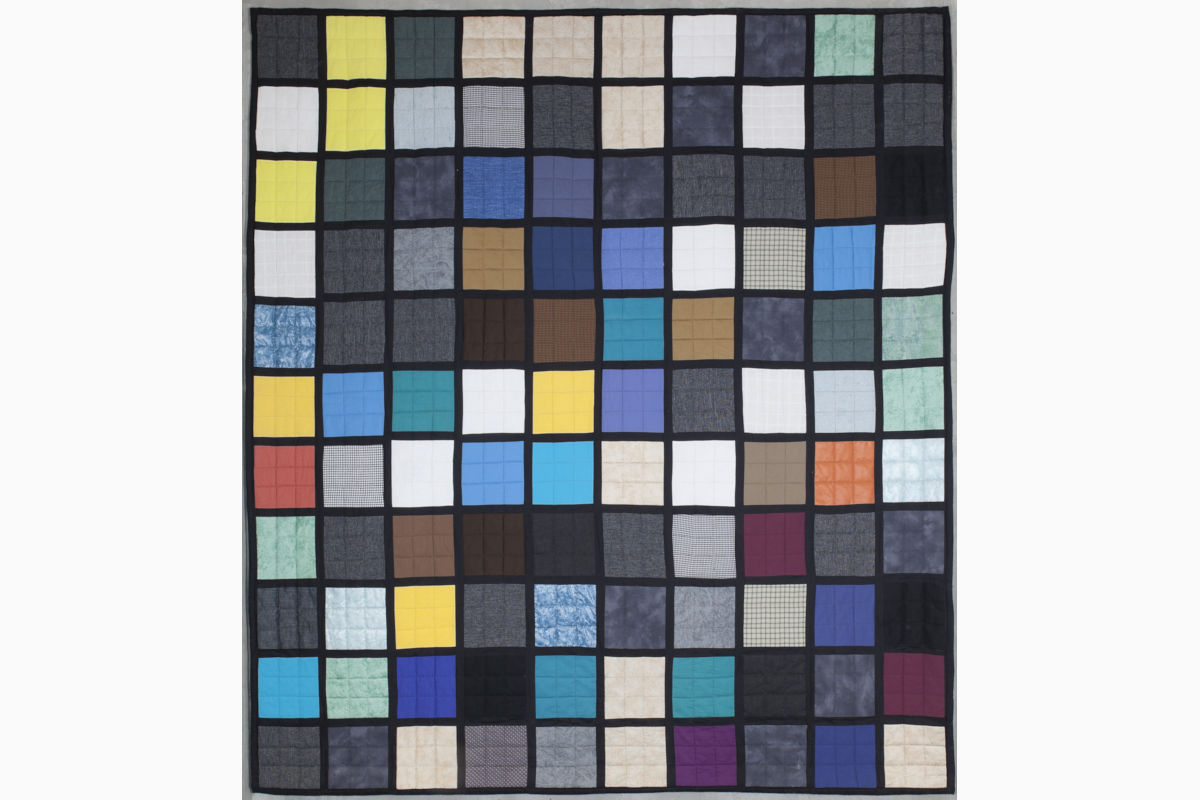 Sabine Cibert X2 ©Philippe-Liev Pourcelot Patchwork quilt with a grid of multicolored squares bordered by dark lines, forming a checker-like mosaic pattern.