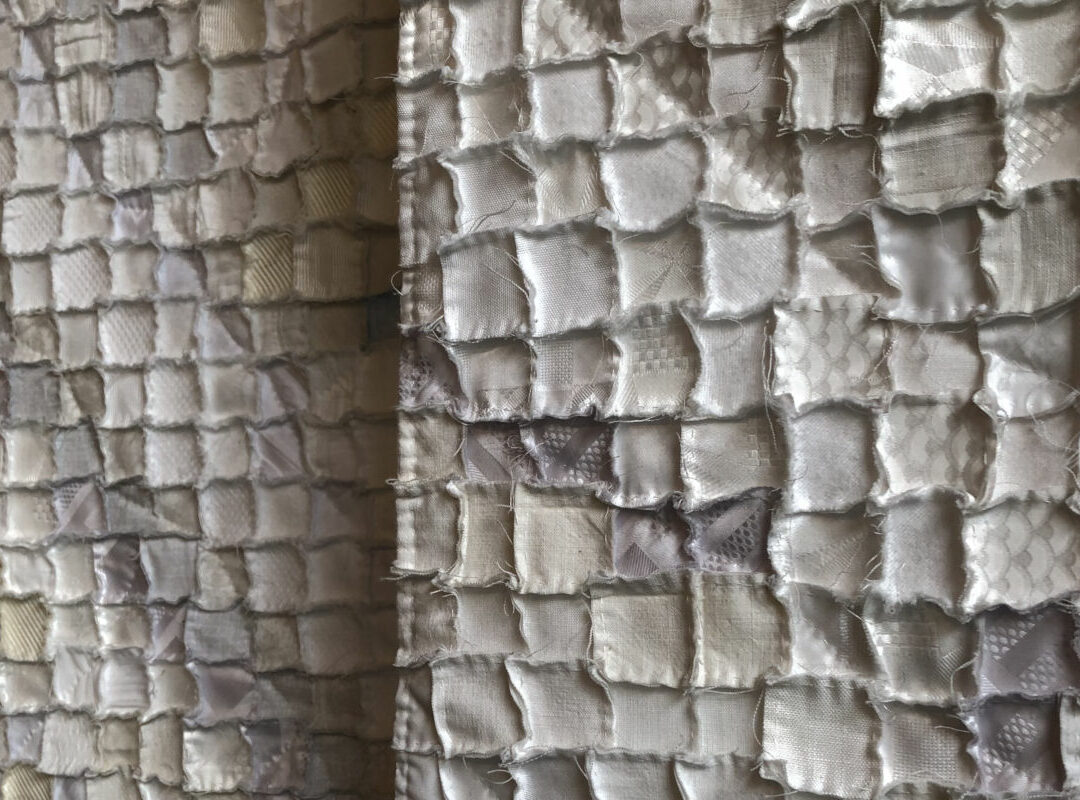 Sabine Cibert Avalanches 1 et 2 detail ©Thomas Leveugle Close-up of a quilted fabric wall hanging made of small square patches in neutral beige and gray tones.