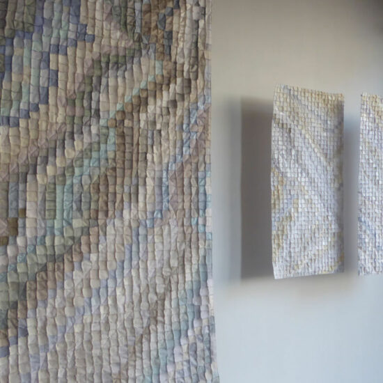 Large multicolored mosaic panel with small square tiles on a wall, flanked by two smaller mosaic canvases on the right.