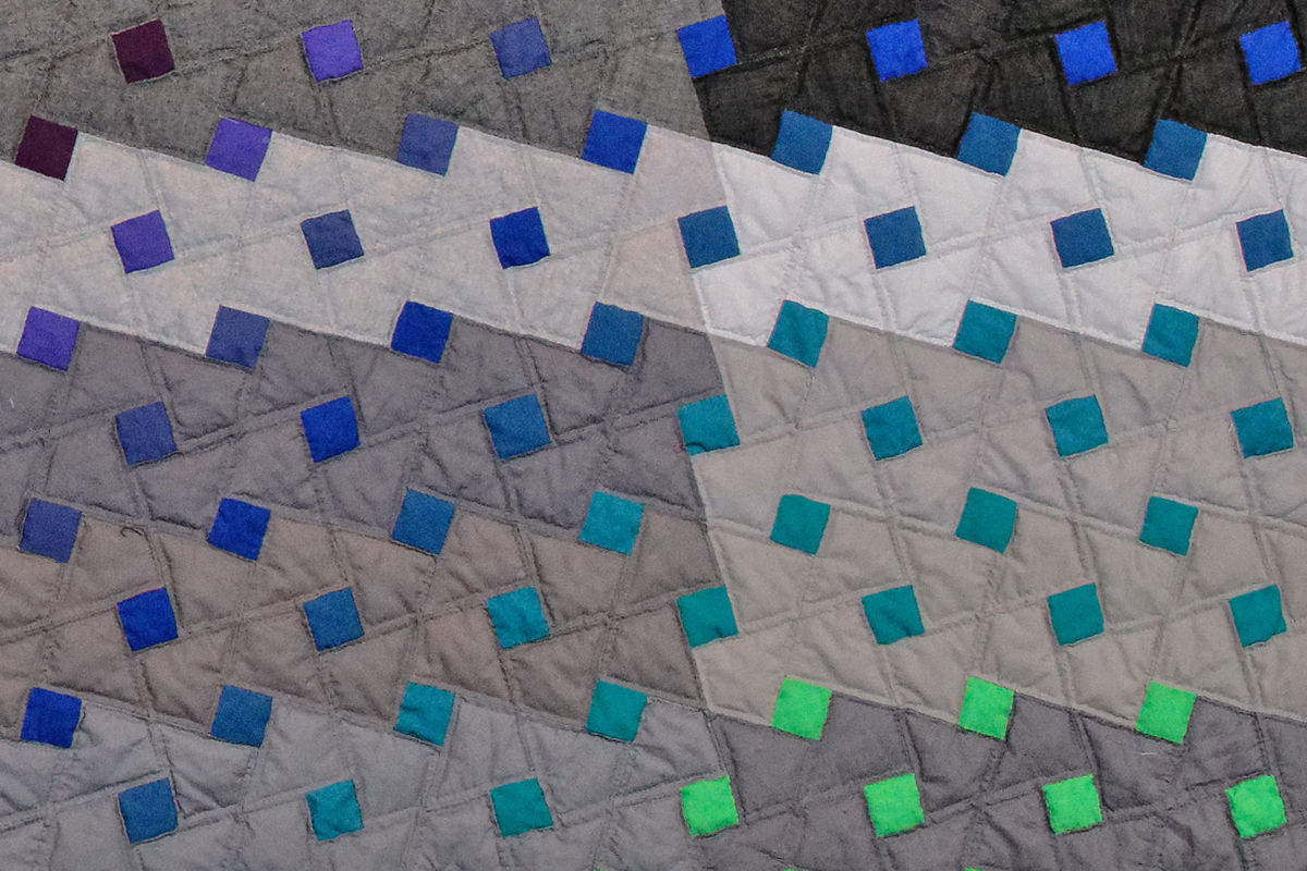 Sabine Cibert Pluie de couleur 2 - détail ©Pascal Muradian Quilted textile pattern with stitched diamonds and small blue-green squares on gray fabric.